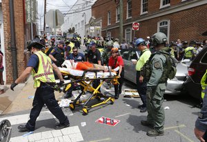 Rescue personnel help injured people after a car ran into a large group of protesters after an white nationalist rally in Charlottesville, Va., Saturday, Aug. 12, 2017.