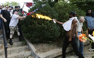 A counter demonstrator uses a lighted spray can against a white nationalist demonstrator at the entrance to Lee Park in Charlottesville, Virginia, Saturday, Aug. 12, 2017.