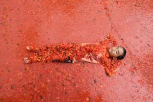 In this Sunday, Aug. 5, 2017, file photo, a boy lies in a pool of tomatoes during the Tomato Festival in Hwacheon, South ...