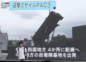 A man walks past a huge screen showing an file image of a PAC-3 Patriot missile unit during a TV news in Tokyo Saturday, Aug. 12, 2017.