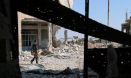 A Free Syrian Army fighter carries his weapon as he walks past damaged buildings in a rebel-held part of the southern city of Deraa, Syria, on July 9, 2017. Photo: Reuters / Alaa Al-Faqir