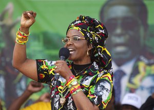 FILE -- In this July 29, 2017 file photo Zimbabwe's First Lady Grace Mugabe greets supporters at a rally in  Zimbabwe. South Africa's police minister says the wife of Zimbabwe's president, background image, has handed herself over to police after being accused of assaulting a young woman Sunday night. (AP Photo/Tsvangirayi Mukwazhi, File)