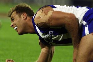 Wayne Carey winces in pain from a shoulder injury. He played on.