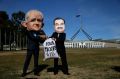 Protestors wearing suits resembling Prime Minister Malcolm Turnbull and Adani chief, Gautam Adani, take part in a ...