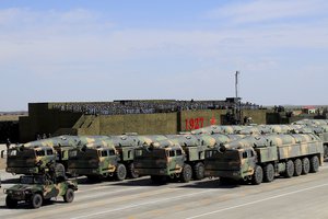 In this photo released by China's Xinhua News Agency, military vehicles carrying missiles for both nuclear and conventional strikes drive past the VIP stage during a military parade to commemorate the 90th anniversary of the founding of the PLA at Zhurihe training base in north China's Inner Mongolia Autonomous Region, Sunday, July 30, 2017.