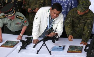 Philippine President Rodrigo Duterte checks a Chinese-made CS/LR4A sniper's rifle during the presentation of thousands of rifles and ammunition by China to the Philippines Wednesday, June 28, 2017, at Clark Airbase in northern Philippines.