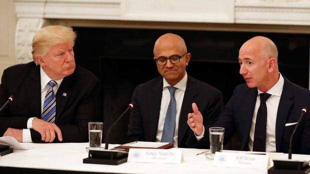 Not much love lost: Donald Trump (with Microsoft CEO Satya Nadella in the centre) listens to Amazon boss Jeff Bezos ...