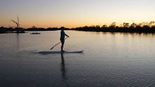 Jenna Brook stand-up paddle boarding in a billabong near Birdsville