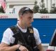 A Uniformed Secret Service officer standing watch near storage containers line the driveway as the West Wing of the ...