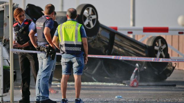 Police officers stand near an overturned car at the spot where terrorists were intercepted by police in Cambrils on Friday.