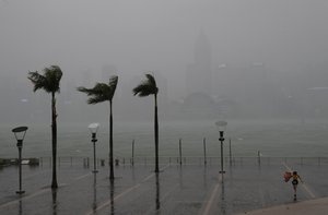 A woman braves the wind on the waterfront of Victoria Habour as Typhoon Haima approaches Hong Kong, Friday, Oct. 21, 2016.