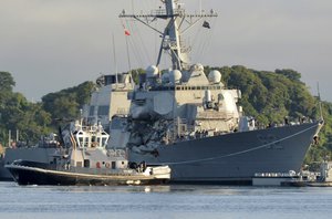 In this July 11, 2017 photo provided by U.S. Navy Office of Information, the Valiant-class yard tugboat Menominee (YT 807) assists the Arleigh Burke-class guided-missile destroyer USS Fitzgerald (DDG 62) as it moves to Dry Dock 4 at Fleet Activities (FLEACT) Yokosuka, Japan, to continue repairs and assess damage sustained from its June 17 collision with a merchant vessel.