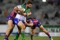 Dave Taylor of the Raiders (centre) is tackled by Daniel Levi of the Newcastle Knights.