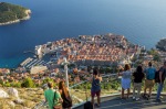 Popular summer travel destination: Tourists at a vantage point looking at the Old Town of Dubrovnik in Croatia from above.