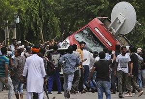 Dera Sacha Sauda sect members overturn an OB van on the streets of Panchkula, India, Friday, Aug. 25, 2017.