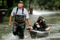 People evacuate a neighborhood inundated by floodwaters from Tropical Storm Harvey on Monday.