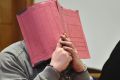 Former nurse Niels Hoegel, accused of multiple murder and attempted murder of patients, covering his face with a file at ...