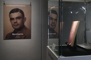 A notebook of British mathematician and pioneer in computer science Alan Turing, the World War II code-breaking genius, is displayed in front of his portrait during an auction preview in Hong Kong Thursday, March 19, 2015. The 56-page manuscript, containing Turing's complex mathematical and computer science notations, is being sold by Bonhams in New York on April 13 and expected to bring at least  US$1 million. (AP Photo/Kin Cheung)