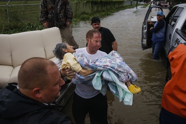 A rescuer moves Paulina Tamirano, 92, from a boat to a truck bed as people evacuate from the Savannah Estates neighborhood as Addicks Reservoir nears capacity Tuesday in Houston.
