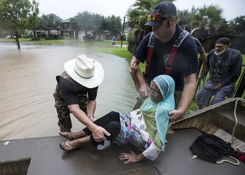 Fort Bend County Sheriff Troy Nehls, left, helps Mumtaz Kara and her husband, Tarmohamed Kara, far right, in the Orchard Lakes subdivision on Sunday.