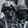 Armed police keep watch as men suspected of being Marawi militants arrive at the Department of Justice in Manila in July.