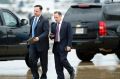 Former White House Chief of Staff Reince Priebus, with phone, walks in the rain.