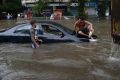 A man sits on a car that got stuck in a waterlogged street following heavy rains in Mumbai.