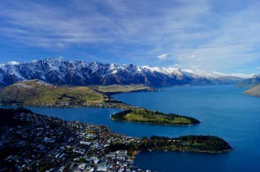 The scenic view of The Remarkables Mountain Range & city of Queenstown, New Zealand. As seen from the Skyline ...