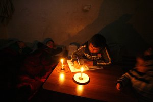 File - Palestinians spend their family time by candlelight at their family's house during a power cut in Rafah refugee camp in southern Gaza Strip on March15, 2014.