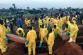 Volunteers handle coffins during a mass funeral for victims of heavy flooding and mudslides in Regent at a cemetery in ...
