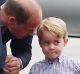 Britain's Prince William, left, holds the hand of his son Prince George on arrival at the airport, in Warsaw, Poland, ...