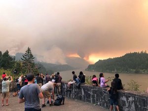 This Sept. 4, 2017, photo provided by Inciweb shows people at a viewpoint overlooking the Columbia River watching the Eagle Creek wildfire burning in the Columbia River Gorge east of Portland, Ore.  A lengthy stretch of highway Interstate 84 remains closed Tuesday, Sept. 5, 2017, as crews battle the growing Eagle Creek wildfire that has also caused evacuations and sparked blazes across the Columbia River in Washington state.   (Inciweb via AP)