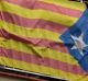 A woman looks out from her balcony decorated with an Estelada or pro-independence Catalan flag and a banner calling for ...