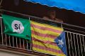 A woman looks out from her balcony decorated with an Estelada or pro-independence Catalan flag and a banner calling for ...