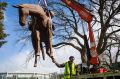 Exhibition production officer Yuri Humeniuk installs Andy Townsend and Suzie Bleach's sculpture 'A Burden' on the ...