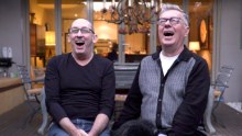 Two men wearing glasses having a big laugh with their mouths open.