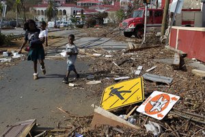 A woman with her two children walk past debris left by Hurricane Irma in Charlotte Amalie, St. Thomas, U.S. Virgin Islands, Sunday, Sept. 10, 2017