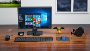 Computer monitor running with Microsoft Windows 10 operation system on table, with devices as headphone, cellphone (smartphone) computer mouse and keyboard