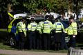 Police and community support officers gather round a police vehicle near where the incident happened.