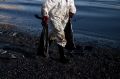 A worker carries fuel oil in bags as he cleans a polluted beach in the island of Salamina near Athens, on Friday.