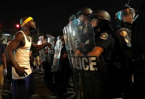 A man yells at police in riot gear just before a crowd turned violent Saturday, Sept. 16, 2017, in University City, Mo.