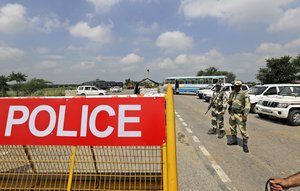 Indian policemen stand guard at a temporary road blockade near Sunaria Jail where Dera Sacha Sauda sect chief Gurmeet Ram Rahim Singh is lodged in Rohtak, some 80 kilometers (50 miles) from New Delhi, India, Monday, Aug. 28, 2017.