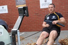 Former electronics warfare submariner in the Australian Navy Richard Wassell training on his rowing machine in the car park 