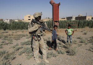 A U.S. soldier stands near Syrian children on a road that links to Raqqa, Syria, Wednesday, July 26, 2017