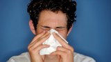 A man blowing his nose with a tissue