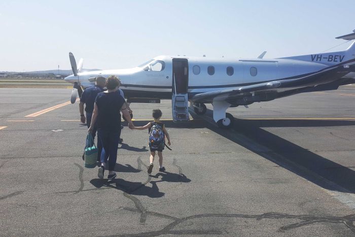 Neil Irwin with his mother and son walking up to the private aeroplane they took to his AFL grand final.