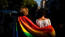 A couple wrapped in rainbow flag taking part in gay pride march. 