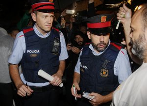 Police officers of the Mossos d'Esquadra, Catalan police, check the I.D. of a person at a school listed to be a polling station by the Catalan government at the Gracia neighborhood in Barcelona, Spain, early Sunday, Oct. 1, 2017.