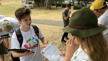 A person wearing a Yes equality t-shirt speaks to someone holding a piece of paper that says conversation guide