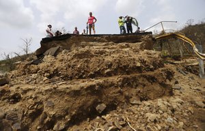 In this Wednesday, Sept. 27, 2017, file photo, residents look over the edge of a bridge that was swept away by Hurricane Maria, which traversed the San Lorenzo de Morovis River, in Morovis, Puerto Rico.